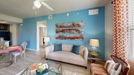 Located in Fort Myers, Florida, this single-story, 3-bedroom, 2-bathroom home offers a thoughtfully designed floor plan that balances comfort and functionality. The open-concept kitchen and living area serves as the heart of the home, featuring wood-look flooring, dark espresso cabinetry, granite countertops, a breakfast bar with seating, and black appliances. A tray ceiling adds architectural dimension to the kitchen space. The living room is highlighted by a bold teal accent wall, ceiling fan, and large windows dressed with decorative curtains that invite natural light and outdoor views.

Each of the three bedrooms showcases its own distinct character through vibrant accent walls — including deep teal and warm orange — along with carpeted floors and ceiling fans for comfort. The primary bedroom is generously sized with ample closet space. The two bathrooms are well-appointed: one features a dual-sink vanity with dark cabinetry, a glass-enclosed walk-in shower, and wood-look tile flooring, while the second offers a classic tub-shower combination with white subway tile. Three closets and a hallway complete the layout, providing practical storage throughout this stylish Fort Myers home.