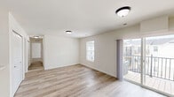 Located at Boone Street Commons in Troy, Missouri, this 2-bedroom, 2-bathroom single-floor unit offers a clean, modern design throughout. The kitchen is a standout feature, showcasing crisp white shaker-style cabinetry extending to the ceiling for ample storage, marble-look countertops, a peninsula layout, and a full suite of stainless steel appliances including a refrigerator, range, and over-the-range microwave. Light hardwood-style flooring runs consistently through all areas of the unit, creating a cohesive and bright aesthetic. The living room is an open, well-lit space featuring multiple windows that invite natural light and a sliding glass door providing additional brightness and outdoor access. The generously sized primary bedroom includes a large double-door closet and an en-suite bathroom, offering a comfortable private retreat. The second bedroom also features closet space and a similarly bright, neutral palette. Both bathrooms are finished with white vanity cabinetry, tub-shower combinations, and chrome fixtures. A connecting hallway ties the bedrooms and bathrooms together efficiently. Throughout the unit, neutral wall tones and consistent flooring create a cohesive, move-in-ready atmosphere well-suited for comfortable everyday living.