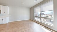 Located at 7831 E Union Ave in Denver, CO, this thoughtfully designed single-floor unit offers a clean, contemporary aesthetic throughout. The open-plan layout seamlessly combines the kitchen, dining, and living areas into one cohesive space, maximizing functionality and flow. The kitchen is outfitted with white shaker-style cabinetry, a classic subway tile backsplash, stainless steel appliances including a range, microwave, and dishwasher, and light-toned countertops. Warm-toned hardwood-style flooring runs continuously throughout the unit, adding a sense of brightness and continuity. The living area is anchored by a generous floor-to-ceiling window that floods the space with natural light and frames views of the surrounding Denver cityscape. The bathroom features a full soaking tub and shower combo with elegant marble-style tile surround and chrome fixtures. Practical elements include an in-unit laundry area with a stacked washer and dryer, two closets for ample storage, and a dedicated utility room. Recessed lighting, a neutral color palette of soft whites and warm grays, and black hardware accents throughout give the space a modern, polished finish. The entry features a keypad-secured door, adding a layer of convenience and security.