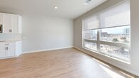 Located at 7831 E Union Ave in Denver, CO, this thoughtfully designed single-floor unit offers a clean, contemporary aesthetic throughout. The open-plan layout seamlessly combines the kitchen, dining, and living areas into one cohesive space, maximizing functionality and flow. The kitchen is outfitted with white shaker-style cabinetry, a classic subway tile backsplash, stainless steel appliances including a range, microwave, and dishwasher, and light-toned countertops. Warm-toned hardwood-style flooring runs continuously throughout the unit, adding a sense of brightness and continuity. The living area is anchored by a generous floor-to-ceiling window that floods the space with natural light and frames views of the surrounding Denver cityscape. The bathroom features a full soaking tub and shower combo with elegant marble-style tile surround and chrome fixtures. Practical elements include an in-unit laundry area with a stacked washer and dryer, two closets for ample storage, and a dedicated utility room. Recessed lighting, a neutral color palette of soft whites and warm grays, and black hardware accents throughout give the space a modern, polished finish. The entry features a keypad-secured door, adding a layer of convenience and security.