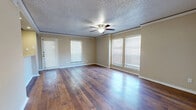 This single-floor, 2-bedroom, 2-bathroom residence offers a practical and comfortable layout across a compact yet efficiently utilized footprint. The spacious living room immediately stands out, featuring rich hardwood flooring, crown molding, a ceiling fan with integrated lighting, and multiple windows fitted with blinds that allow for generous natural light. A glass-panel door provides additional brightness and potential outdoor access.

The kitchen is designed for functionality, equipped with stainless steel appliances including a refrigerator, electric range, and over-the-range microwave. Dark espresso cabinetry paired with light countertops provides an appealing contrast, while hardwood flooring continues throughout the space.

Both bathrooms are consistently appointed with dark wood vanities, granite-style countertops, full tub-shower combinations with white tile surrounds, and accessible grab bars. Hardwood flooring carries through each bathroom as well.

The two bedrooms offer a contrast in flooring — one features plush carpeting with a ceiling fan and a sliding-door closet, while the primary bedroom also showcases soft carpet and a ceiling fan, with a large vertical-blind-covered door offering natural light. The space is completed by a dedicated hallway and closet, contributing to organized, efficient living throughout.