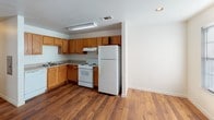 This single-story residence offers a well-organized layout designed for comfortable everyday living. The living area serves as the heart of the home, featuring rich hardwood-style flooring, a ceiling fan with light fixture, and a sliding glass door covered by vertical blinds that allows natural light to fill the space. A six-panel front door provides a welcoming entry point.

The kitchen is equipped with warm honey-toned wood cabinetry extending to the upper walls, offering generous storage. White appliances, including a freestanding electric range and refrigerator, complement the functional design, while recessed lighting and a built-in overhead fixture illuminate the workspace. Hardwood-style flooring continues throughout the kitchen.

The bedrooms are carpeted for comfort, each featuring a ceiling fan or window with blinds, providing natural light and ventilation. The two bathrooms include a bathtub and shower combination with chrome fixtures and grab bars. One bathroom features a white vanity with a mirror and lighted bar, dark wood wall cabinet, and hardwood-style flooring, while the second offers a tan countertop vanity and textured walls, maintaining a clean and practical aesthetic throughout.