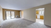 Located at 205 Charlotte Court in Central Valley, NY, this two-bedroom, two-bathroom residence offers a well-organized single-floor layout designed for comfortable everyday living. The open living room features soft carpeting, warm neutral tones, and sliding glass doors that invite natural light and provide access to outdoor views of surrounding greenery. Adjacent to the living area, the dining room is accented by a classic brass chandelier and a large window framing picturesque wooded scenery, creating an inviting atmosphere for meals.

The kitchen is outfitted with warm honey-toned wood cabinetry extending to the ceiling for ample storage, light countertops, and tile flooring, with a full suite of white appliances including a range and refrigerator. A hallway connects the main living spaces to the private quarters, where two carpeted bedrooms offer restful retreats. The generously sized primary bedroom includes a walk-in closet and a large window overlooking the natural landscape. Five closets throughout the home provide exceptional storage capacity.

The two bathrooms are finished with classic white tile wainscoting; one features a shower stall, while the other includes a full tub-shower combination. A dedicated family room and entrance area round out this well-appointed home.