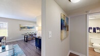 Located at 202 Lingstorm Ln in North Chesterfield, VA, this single-floor, one-bedroom, one-bathroom residence offers a thoughtfully designed layout that maximizes every square foot of living space. The living room serves as the welcoming heart of the home, featuring hardwood-style flooring, a shiplap-accented feature wall, and a large window fitted with blinds that allows natural light to fill the space while offering a view of the surrounding greenery. The galley-style kitchen is efficiently designed with white cabinetry, granite countertops, a stainless steel sink, and black stainless appliances including a range, microwave, and refrigerator, all complemented by hardwood-style flooring and a flush-mount ceiling light. The spacious bedroom is carpeted for comfort and includes a window providing natural light, wall-mounted TV space, and convenient in-unit stacked washer and dryer within a dedicated closet — a rare and practical feature. The bathroom is clean and bright, finished with white square tile surrounding a full soaking tub and shower combination with chrome fixtures. A connecting hallway links all rooms cohesively, completing this compact yet functional and comfortable living space.