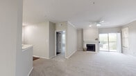 This single-floor residence is designed with a neutral, contemporary palette and a practical, open layout. The living area is spacious and carpeted, anchored by a classic white-mantled fireplace and accented with crown molding. A ceiling fan provides comfort, while a sliding glass door opens to a balcony with outdoor views, allowing natural light to fill the room. Built-in shelving adds functional storage and character to the living space.

The kitchen features white raised-panel cabinetry, light stone countertops, a mosaic tile backsplash, and a full suite of white appliances. A peninsula counter with a sink opens to the living and dining areas, creating a connected, flowing feel. Wood-look flooring grounds the kitchen with warmth.

The bedrooms are carpeted and bright, with ceiling fans and generous windows that invite natural light and views of surrounding greenery. Ample closet space is present throughout.

The bathrooms are finished with wood-look flooring, light cabinetry, and white countertops. One bathroom offers a walk-in glass-enclosed shower, while the other includes a full tub-shower combination with marble-style surround. Together, they reflect a clean, functional design consistent with the rest of the home.