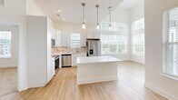 Located at 200 Brooklawn St in Farragut, TN, this well-appointed 2-bedroom, 2-bathroom single-floor home offers a bright, modern living experience. The open-concept kitchen and living area is a standout feature, boasting soaring ceilings, large windows that flood the space with natural light, and sweeping outdoor views. The kitchen is equipped with stainless steel appliances, white shaker cabinetry, a tasteful tile backsplash, pendant lighting over a central island with white countertops, and light hardwood-style flooring that extends throughout the main living areas. The spacious living room is anchored by a ceiling fan and opens seamlessly to the kitchen, creating an ideal layout for everyday living. The primary bedroom is generously sized with elevated ceilings, a ceiling fan, and direct access to a well-designed en-suite bathroom featuring an extended dual-sink vanity with white cabinetry, a large mirror, and hardwood-style flooring. The second bedroom is comfortable and bright, with plush carpeting and a window offering neighborhood views. Both bedrooms include closet space. The hallways feature built-in shelving niches, adding both character and functionality. The overall aesthetic is clean, contemporary, and airy throughout.