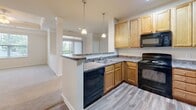 Located at Abberly Village Circle in West Columbia, SC, this well-appointed 2-bedroom, 2-bathroom residence offers a thoughtfully designed single-floor layout. The open-concept living and dining area features plush carpeting, recessed lighting, decorative columns, and a tray ceiling with a ceiling fan. A sliding glass door floods the space with natural light and provides access to a private balcony with outdoor views.

The kitchen is equipped with warm wood cabinetry, granite-style countertops, black appliances including a gas range, dishwasher, and refrigerator, and a peninsula breakfast bar illuminated by pendant lighting — ideal for casual dining or entertaining.

The generously sized primary bedroom features a tray ceiling, a ceiling fan, a walk-in closet, and a large window overlooking the surrounding community. The en-suite bathroom includes a walk-in glass shower and wood-look flooring. The second bedroom also benefits from a tray ceiling, a ceiling fan, a closet, and a bright window. The second bathroom offers a full tub-shower combo, granite-style vanity, and wood-look flooring.

Additional highlights include a dedicated laundry area with in-unit washer and dryer hookups and wood-look flooring throughout the non-carpeted areas, completing this functional and comfortable home.