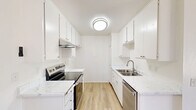 This 2-bedroom, 2-bathroom residence in Chino, CA offers a thoughtfully arranged single-floor layout that makes efficient use of its space. The galley-style kitchen is a standout feature, showcasing crisp white cabinetry, quartz-style countertops, light wood-look flooring, and stainless steel appliances including an electric range and dishwasher — all beneath a clean flush-mount ceiling light. The kitchen opens toward a dining area with a ceiling fan and a window that invites natural light. The living room is carpeted and spacious, with a sliding glass door that leads to a private balcony offering outdoor views, complemented by a skylight overhead and a textured ceiling throughout. Both bedrooms are carpeted and bathed in natural light from well-placed windows. The primary bedroom is generously sized and includes a wide sliding-door closet with ample storage. The two bathrooms each feature a tub-shower combination enclosed by sliding frosted glass doors. The primary bathroom is further enhanced by a large vanity mirror and marble-style countertops, adding a refined touch. White walls and neutral tones throughout the home create a clean, airy ambiance that is both functional and inviting.