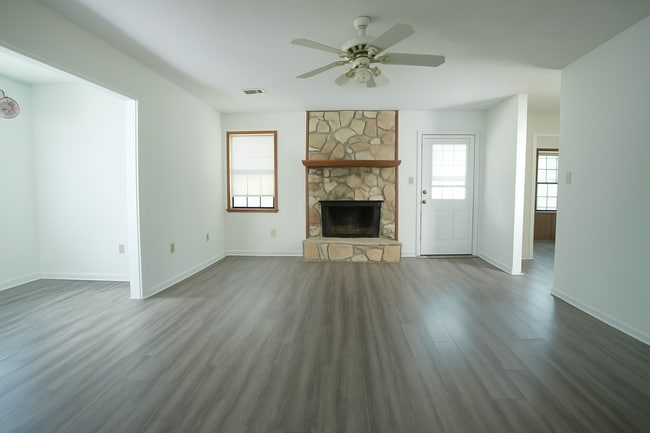 Open living space with stone fireplace, wood-look floors, and bright bonus room. - 2313 Salem West Dr