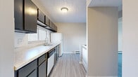 Located at 730 Pine Knolls Dr in Akron, Ohio, this two-floor unit is defined by a clean, neutral aesthetic and functional layout throughout. Light gray vinyl plank flooring runs consistently across both levels, creating a cohesive and easy-to-maintain surface underfoot.

The main level features a well-proportioned living area with sliding glass doors that invite natural light and provide outdoor access. A wall-mounted air conditioning unit and baseboard heating system ensure year-round comfort. The kitchen is outfitted with dark cabinetry extending to the ceiling for generous storage, light countertops, a double-basin sink beneath a window, and white appliances including a refrigerator and dishwasher. A textured ceiling and flush-mount lighting complete the space.

A striking black spiral staircase serves as a visual focal point on the main level, connecting to the upper floor. Upstairs, the bedrooms feature neutral walls, ceiling fans, and baseboard heating. One bedroom includes a built-in closet with shelving. The bathroom is equipped with a vanity, soaking tub, and towel bars. Throughout both floors, the understated color palette and clean finishes contribute to a bright, move-in-ready atmosphere.