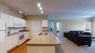 Located at 1903 N Lincoln Ave in Urbana, Illinois, this single-floor unit offers a well-designed, functional layout ideal for everyday living. The open-concept kitchen flows seamlessly into the living area, creating a connected and social atmosphere. The kitchen is equipped with white cabinetry, laminate countertops, white appliances including a refrigerator, electric range, and built-in microwave, as well as a peninsula with a double sink that serves as both a workspace and a casual dining divider. Track lighting illuminates the kitchen, adding a modern touch. A dedicated in-unit laundry area with a washer is conveniently tucked adjacent to the kitchen. The carpeted living room provides a comfortable gathering space with crown molding and a window that brings in natural light and outdoor views of surrounding greenery. Multiple bedrooms are carpeted and offer ample natural light; one bedroom features a large multi-pane window overlooking trees, creating a serene retreat. The bathrooms feature tile flooring and a clean, simple design. Throughout the unit, six-panel interior doors and neutral warm tones contribute to a cohesive and welcoming aesthetic. The thoughtful floor plan, in-unit laundry, and open living spaces make this a practical and comfortable home.