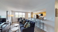 This single-floor residence offers a thoughtfully designed layout with two bedrooms and two bathrooms. The open-concept living and dining area is bright and welcoming, with multiple large windows that invite natural light and offer pleasant outdoor views. The living space flows seamlessly into a peninsula-style kitchen, where warm honey-toned cabinetry pairs with dark granite countertops and stainless steel appliances, including a gas range, refrigerator, and built-in microwave. Track lighting illuminates the galley-style kitchen, which features tile flooring and generous cabinet storage throughout.

The primary bedroom is carpeted and comfortably sized, featuring a closet with bifold doors and windows that bring in natural light. The second bedroom is similarly appointed, with dual windows framing tree views and baseboard heating. A cozy sitting nook with additional windows provides a quiet retreat. Both bathrooms are finished with tile flooring and clean white fixtures, with one featuring a tub-shower combination. The overall ambiance is calm and neutral, with consistent finishes creating a cohesive, livable environment throughout.