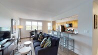 This single-floor residence offers a thoughtfully designed layout with two bedrooms and two bathrooms. The open-concept living and dining area is bright and welcoming, with multiple large windows that invite natural light and offer pleasant outdoor views. The living space flows seamlessly into a peninsula-style kitchen, where warm honey-toned cabinetry pairs with dark granite countertops and stainless steel appliances, including a gas range, refrigerator, and built-in microwave. Track lighting illuminates the galley-style kitchen, which features tile flooring and generous cabinet storage throughout.

The primary bedroom is carpeted and comfortably sized, featuring a closet with bifold doors and windows that bring in natural light. The second bedroom is similarly appointed, with dual windows framing tree views and baseboard heating. A cozy sitting nook with additional windows provides a quiet retreat. Both bathrooms are finished with tile flooring and clean white fixtures, with one featuring a tub-shower combination. The overall ambiance is calm and neutral, with consistent finishes creating a cohesive, livable environment throughout.