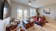 Located in Garland, TX, this 2-bedroom, 2-bathroom single-story residence offers a thoughtfully designed open-concept layout that seamlessly connects the living, dining, and kitchen areas. The living room features light wood-style flooring, a ceiling fan, built-in shelving, and large windows and glass doors that fill the space with natural light while providing access to an outdoor balcony with open views. The dining area is situated adjacent to the living room and benefits from its own window, adding to the bright and airy feel of the shared space. The galley-style kitchen is equipped with rich dark cabinetry, light countertops, stainless steel appliances including a refrigerator, stove, and microwave, and a double-basin sink — combining functionality with a clean, modern aesthetic. The primary bedroom is a comfortable retreat featuring plush carpet, a ceiling fan, ample natural light from a large window, and a built-in nook for additional storage. The bathrooms are finished with marble-style tile flooring and surround, dark wood cabinetry, and light countertops, offering a polished, contemporary look. A hallway connects the private areas of the home, completing this well-organized and stylish single-floor layout.