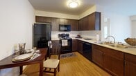 Located at 4112 133rd St SE in Mill Creek, Washington, this single-floor residence offers a well-organized layout designed for comfortable everyday living. The kitchen is a functional centerpiece, outfitted with rich dark espresso cabinetry, light countertops, and a full suite of black appliances including a refrigerator, range, microwave, and dishwasher. Warm hardwood-style flooring flows through the kitchen and dining area, which comfortably accommodates a dining table and chairs. The living area features plush carpeting, a sliding glass door with vertical blinds that opens to a balcony, and a bright, open feel. Multiple bedrooms are carpeted and bathed in natural light from windows with vertical blinds. Each bedroom benefits from generous closet space, including walk-in closets with wire shelving systems that provide ample storage. The bathroom features a wide vanity with dark wood cabinetry, a large mirror, and bright overhead lighting. Throughout the residence, neutral wall tones and clean finishes create a cohesive, understated aesthetic. The layout, as reflected in the dollhouse view, is efficiently organized with clear separation between living, sleeping, and functional spaces, making this Mill Creek home both practical and inviting.