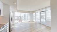 Located in the heart of downtown San Diego, this contemporary high-rise unit offers three bedrooms, two bathrooms, and a thoughtfully designed open layout. The living, dining, and kitchen areas flow seamlessly together, bathed in abundant natural light streaming through expansive floor-to-ceiling windows that frame sweeping panoramic views of the San Diego skyline. Light wood-tone flooring runs throughout, complementing the bright, neutral palette that defines the space. A private balcony extends the living area outdoors, offering elevated city views. The sleek kitchen is appointed with white flat-front cabinetry, a gray tile backsplash, light countertops, and a full suite of stainless steel appliances including a refrigerator, range, microwave, and dishwasher. The bathrooms feature marble-style tile surrounds, undermount sinks with modern fixtures, and large mirrors. Each of the three bedrooms is generously proportioned, with the primary bedroom benefiting from oversized windows showcasing impressive skyline vistas. Three dedicated closets provide ample storage throughout. A hallway connects the private quarters to the main living areas, and an in-unit laundry room adds everyday convenience. Clean architectural lines and an abundance of natural light define the overall ambiance of this modern urban residence.