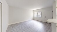 This 570 square foot apartment in Hialeah, FL offers a efficient living space with 2 bedrooms and 2 bathrooms. The primary bedroom is generously sized at 170 square feet. The interior boasts modern finishes throughout, with sleek gray laminate flooring and crisp white walls creating a bright, contemporary aesthetic. The kitchen features white cabinetry, stainless steel appliances, and ample counter space. Bathrooms are outfitted with modern fixtures, including a tub/shower combination with neutral tile surround. Large windows in the living areas and bedrooms allow for plenty of natural light. The apartment is part of a multi-story complex with a tropical flair, showcasing palm trees and colorful landscaping. Residents enjoy private balconies with metal railings, perfect for enjoying the Florida climate. The building's exterior features a white and red color scheme, adding to its resort-like appearance.