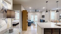 This thoughtfully designed 2-bedroom, 2-bathroom residence in Little Rock, Arkansas offers a functional and modern single-floor layout. The open-concept living and kitchen area serves as the heart of the home, with light wood-look flooring flowing throughout. The kitchen is outfitted with stainless steel appliances, dark cabinetry on the lower level, crisp white upper cabinets, a grey subway tile backsplash, granite countertops, and a peninsula with pendant lighting overhead. The living room connects seamlessly to the kitchen and features a ceiling fan and French doors that invite natural light and outdoor views. Both bedrooms are carpeted and equipped with ceiling fans; the primary bedroom offers a closet and private bathroom access, while the second bedroom includes a window with natural light. The two bathrooms are finished with granite-topped dark vanities, large mirrors, and tile-style flooring. A dedicated laundry room with side-by-side washer and dryer hookups and built-in shelving adds everyday convenience. Neutral tones, recessed lighting, and clean finishes throughout give this residence a cohesive and contemporary feel.