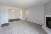 Located at 12000 Candelaria Rd NE in Albuquerque, New Mexico, this single-floor residence offers a well-organized and functional layout designed for comfortable everyday living. The living area serves as the centerpiece of the home, featuring plush wall-to-wall carpeting and a standout corner fireplace with a white tile surround and built-in niche above — an inviting focal point for the room. A large sliding glass door fills the space with natural light while providing direct access to an outdoor balcony with views of the surrounding neighborhood. An adjacent dining or flex area is distinguished by rich hardwood-style flooring and a ceiling fan, creating a warm, defined space that connects seamlessly to the main living area. The kitchen is outfitted with white cabinetry, light stone-look countertops, and stainless steel appliances including an electric range and over-the-range microwave. The bedroom continues the carpeted aesthetic and is bright and spacious, featuring a ceiling fan, a closet, and its own sliding glass door opening to a private balcony. The bathroom is clean and efficiently designed, offering a single-sink vanity with a stone-look countertop, hardwood-style flooring, and a full tub-shower combination with white tile surround.