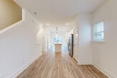 Located in Charlotte's Prosperity Commons community, this contemporary multi-level home offers 3 bedrooms, 5 bathrooms, and a thoughtfully designed layout spread across four floors. The ground level features an attached garage with concrete flooring and ample storage space. The main living floor showcases an open-concept design where the living room flows seamlessly into a well-appointed kitchen. The kitchen is a standout, featuring white shaker cabinetry, a subway tile backsplash, stainless steel appliances, quartz countertops, a central island with a matte black faucet, and geometric pendant lighting. Light-toned luxury vinyl plank flooring runs consistently throughout the home, complementing the clean white walls and recessed lighting. A staircase connects each level with clean lines and neutral finishes. The upper floors house the bedrooms, including a primary suite with its own bathroom. The bedrooms are bright and airy, with multiple windows framing neighborhood views and ceiling fans providing comfort. Five bathrooms serve the home, featuring marble-style tile flooring and modern fixtures. The top floor provides additional flexible living space. This home combines efficient use of space with modern finishes throughout.