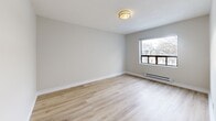 Located at 223 Woodbine Ave in Toronto's vibrant East End, this one-bedroom, one-bathroom unit offers a thoughtfully organized layout across a single floor. Light-toned hardwood-style flooring runs throughout, lending a clean, cohesive look to the entire space.

The living room is the largest area of the unit, featuring a wide window that draws in natural light and offers views of the surrounding neighbourhood. Neutral beige walls and a textured ceiling complement the bright, airy feel of the room. A baseboard heating unit ensures comfortable temperatures year-round.

The kitchen is efficiently designed with white subway tile backsplash, stone-effect countertops, stainless steel appliances including a range and over-the-range microwave, and light cabinetry — all illuminated by a window above the counter.

The bedroom is a private, quiet retreat with its own window, baseboard heater, and the same warm flooring found throughout the unit. Two dedicated closets provide practical storage solutions.

The bathroom is finished in crisp white, featuring a full soaker tub with overhead shower, white tile surround, and a frosted window for natural light and privacy. The overall palette of whites and warm neutrals throughout the unit creates a clean, move-in-ready environment.