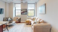 Located at 1401 N 5th St in Philadelphia's vibrant NoLibs neighborhood, this single-floor residence offers a thoughtfully designed layout that blends modern finishes with functional living. Rich hardwood flooring flows throughout, connecting each space with warmth and continuity — from the long, well-lit entry corridor to the open-concept kitchen and living area.

The kitchen is a standout feature, showcasing deep cherry wood cabinetry, granite countertops, stainless steel appliances including a gas range with a sleek overhead hood, and a peninsula with bar seating — ideal for casual dining or entertaining. The adjacent living area is bright and welcoming, benefiting from large windows that frame treetop views and flood the space with natural light.

The bedroom is comfortably sized and finished with crown molding, recessed lighting, and a closet with bifold doors, providing ample storage. The bathroom features sophisticated floor-to-ceiling linear gray tile, a combined tub and shower with a glass sliding door, and a dark-finished vanity with a crisp white countertop.

Throughout the unit, crown molding, recessed lighting, and neutral tones create a clean, cohesive aesthetic. The combination of upscale finishes and practical design makes this a well-rounded urban residence.