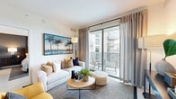 Located in Miami's vibrant urban core, this 2-bedroom, 2-bathroom unit at 999 NW Seventh St offers a well-appointed, modern layout across a single floor. The open-plan living and kitchen area serves as the heart of the home, bathed in natural light from floor-to-ceiling sliding glass doors that lead to a private balcony featuring a distinctive perforated metal railing. The balcony offers views of a nearby waterway and the surrounding cityscape. The kitchen is equipped with stainless steel appliances, warm wood lower cabinetry, crisp white upper cabinets, a subway tile backsplash, and a clean quartz countertop island — ideal for both cooking and casual dining. Light-toned tile flooring runs throughout, enhancing the bright, airy atmosphere. The spacious primary bedroom features large windows with outdoor views, while the second bedroom is equally well-lit with balcony access. Both bathrooms are cleanly finished with light tile work and wood-toned vanities. A hallway and closet provide practical storage, while the entryway offers a welcoming transition into the living space. The overall aesthetic is contemporary and cohesive, reflecting a clean Miami-modern design sensibility.