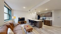 Located on Euclid Avenue in the heart of Cleveland, OH, this well-appointed 2-bedroom, 2-bathroom residence offers a thoughtfully designed single-floor layout with modern finishes throughout. The open-concept living and kitchen area serves as the centerpiece of the unit, featuring light wood-look flooring, recessed lighting, and a seamless flow between spaces. The kitchen is equipped with dark espresso cabinetry, stainless steel appliances, a subway tile backsplash, and a large island with a crisp white countertop and bar seating — ideal for both cooking and entertaining. The living area is bright and welcoming, with large windows framing urban downtown Cleveland views. A hallway connects the main living space to the two bedrooms and additional rooms. The spacious primary bedroom includes plush carpeting, a walk-in closet, and a private en-suite bathroom with a glass-enclosed shower and marble-style tile. The second bedroom also features soft carpeting and a frosted interior window. A second full bathroom offers a tub-shower combination with elegant marble-style tile surround. Additional highlights include a dedicated laundry room, generous closet storage, and a well-defined entrance foyer — making this a complete and functional urban residence.