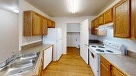 Located in Denham Springs, Louisiana, this single-floor unit offers four bedrooms and two full bathrooms across a well-organized layout. Warm hardwood-style flooring flows consistently throughout the space, lending a cohesive and inviting feel to every room.

The kitchen is designed for functionality, featuring honey-toned wooden cabinetry lining both walls, a double-basin sink, a coil-top electric range, a dishwasher, and a full-size refrigerator. A peninsula counter opens toward the hallway, enhancing the sense of flow between the kitchen and living areas.

The spacious primary bedroom includes a ceiling fan with light fixture and direct access to a walk-in closet. The additional bedrooms are bright and well-proportioned, each featuring hardwood-style flooring, windows with blinds that allow natural light, and closet access. Ceiling fans are present in select bedrooms for added comfort.

Both bathrooms are finished with hardwood-style flooring, warm wood vanity cabinetry, and tub-shower combinations — one featuring a full surround enclosure. A dedicated laundry room includes washer and dryer hookups, a shelf for storage, and hardwood-style flooring, providing convenient in-unit laundry capability. Two hallways connect the rooms efficiently throughout the layout.