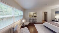 Located at 3542 Minikahda Ct in St. Louis Park, Minnesota, this single-floor residence offers a well-designed, comfortable living space with a cohesive neutral palette and warm hardwood flooring throughout. The open-concept main living area is bathed in natural light from large windows that frame lush greenery views, creating a bright and welcoming ambiance. A seating area flows naturally toward the kitchen, which is accessed through a pass-through bar with seating for several, making it ideal for casual dining and entertaining. The kitchen is thoughtfully appointed with gray shaker-style cabinetry, granite countertops, a classic white subway tile backsplash, and stainless steel appliances. The spacious bedroom is a serene retreat, showcasing rich dark hardwood floors, multiple windows with garden views, and ample room for a dedicated workspace. A door from the bedroom provides direct access to an adjoining area, adding functional versatility. The bathroom features beadboard wainscoting, a clean white vanity, and a framed mirror, lending a timeless and polished character. Throughout the space, clean lines, soft gray tones, and carefully chosen finishes come together to create an environment that is both functional and inviting.