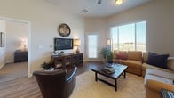 This single-floor residence is thoughtfully designed with an open layout that connects the main living areas seamlessly. The kitchen is a standout feature, showcasing rich dark-wood cabinetry extending to soaring ceiling heights, granite countertops, a subway tile backsplash, and black appliances including a refrigerator, range, and built-in microwave. A central island with pendant lighting provides additional workspace and casual seating. Wood-style flooring runs throughout the main living areas, adding warmth and continuity.

The living room is bright and inviting, featuring large windows with exterior views, wood-style flooring, and a ceiling fan. A secondary sitting area mirrors this comfort with generous natural light.

Multiple bedrooms are carpeted and well-proportioned, each featuring large windows that allow natural light and outdoor views. The primary bedroom connects to a bathroom equipped with dark-wood cabinetry, granite countertops, and wood-style flooring. An additional bathroom includes a tub-shower combination and consistent finishes throughout.

The overall aesthetic is modern and cohesive, blending dark wood tones, neutral walls, and quality materials to create a polished, comfortable living space.