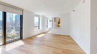Located at 520 N Kingsbury Street in Chicago's River North neighborhood, this efficiently designed studio offers a clean, modern aesthetic throughout its single-floor layout. The open-plan kitchen and living area forms the heart of the space, bathed in natural light streaming through large floor-to-ceiling sliding glass doors and expansive windows that frame views of the Chicago skyline. Light hardwood flooring runs throughout the main living area, lending warmth to the bright white walls and contemporary finishes.

The galley-style kitchen is thoughtfully appointed with warm-toned wood cabinetry, white quartz countertops, a subway tile backsplash, and a full suite of stainless steel appliances including a refrigerator, range, microwave, and dishwasher. A pass-through opening connects the kitchen to the living area, enhancing the sense of openness.

The bathroom features neutral tile flooring, a wood-grain vanity with a white countertop, a large wall mirror, and chrome accents, maintaining the unit's clean and modern character. A dedicated closet provides practical storage. The entry hallway, with light tile flooring, leads seamlessly into the main living space. Overall, the unit presents a bright, minimalist atmosphere well-suited to urban living in one of Chicago's most vibrant neighborhoods.