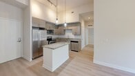 Located at 817 SE Second Ave in Fort Lauderdale, FL, this well-appointed 2-bedroom, 2-bathroom residence offers a thoughtfully designed single-floor layout with contemporary finishes throughout. The open-concept living and kitchen area is anchored by soaring ceilings and a ceiling fan, creating an airy, spacious atmosphere. Large windows and a glass entry door allow abundant natural light and offer views of lush, mature greenery outside.

The modern kitchen is a standout feature, equipped with stainless steel appliances including a refrigerator, range, microwave, and dishwasher. Sleek, textured flat-front cabinetry pairs elegantly with granite countertops that extend to a central island, illuminated by stylish pendant lighting and track lights above.

Both bathrooms are finished with granite-topped wood vanities, large-format tile surrounds, soaking tub-shower combos, and clean neutral tile flooring. The primary bedroom is generously sized, featuring high ceilings, a walk-in closet, and direct access to an en-suite bathroom. The second bedroom benefits from a large window framing verdant outdoor views. Light wood-tone flooring flows consistently throughout, complementing the residence's clean, modern aesthetic.