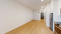 Located at 4603 Minnehaha Ave in Minneapolis, MN, this efficiently designed studio unit offers a thoughtfully organized single-floor layout that maximizes every inch of available space. Light wood flooring runs continuously throughout, lending warmth and visual continuity to the open floor plan.

The kitchen is a standout feature, outfitted with full-height white cabinetry, open shelving with wood accents, a classic white subway tile backsplash, and a full suite of stainless steel appliances including a refrigerator, electric range, over-the-range microwave, and dishwasher. Recessed lighting overhead keeps the space bright and functional.

The living area is open and airy, anchored by a pair of large windows with black frames that invite natural light and provide views of the exterior. A wall-mounted PTAC unit provides climate control. Recessed ceiling lights ensure the space remains well-lit throughout the day and evening.

The full bathroom is clean and modern, featuring white cabinetry with brushed nickel hardware, an undermount sink with a white countertop, a combined tub and shower, and light wood-style flooring. Grab bars are installed alongside the tub and vanity, reflecting a thoughtful, accessibility-conscious design.

A hallway connects all areas of the unit, with in-unit laundry hookups and ample closet storage visible along the corridor. The overall aesthetic is contemporary and minimalist, defined by a crisp white palette and clean lines throughout.