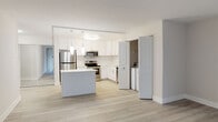 This thoughtfully renovated single-floor residence offers a clean, contemporary aesthetic defined by bright white tones, light wood-look flooring, and a seamless open layout. The kitchen serves as a focal point of the home, showcasing crisp white shaker cabinetry extending to the ceiling, quartz countertops, and a full suite of stainless steel appliances including a refrigerator, electric range, microwave, and dishwasher. A central island provides additional prep and gathering space, while pendant lighting and a flush ceiling fixture illuminate the area warmly. Conveniently tucked just off the kitchen is an in-unit laundry area with a washer and dryer. The living areas feature light-toned plank flooring and large windows dressed with vertical blinds, allowing natural light to fill the space generously. The bedroom is carpeted and includes a wall-unit HVAC system and a window with outdoor views. Two bathrooms complete the unit, both finished with elegant marble-style tile. One bathroom features a soaking tub with shower combination, while the second offers a walk-in glass-enclosed shower — both appointed with white vanities and coordinating fixtures for a polished, cohesive feel throughout.