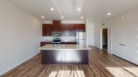 Located at 3745 Technology Dr NW in Rochester, Minnesota, this single-floor unit offers a thoughtfully designed open-concept layout that seamlessly connects the kitchen, dining, and living areas. The kitchen is a standout feature, showcasing rich dark-wood cabinetry extending to the ceiling for ample storage, granite countertops, stainless steel appliances including a range, microwave, and refrigerator, and a center island with a built-in sink — ideal for both cooking and casual dining. Wood-style flooring runs throughout the main living areas, lending warmth and continuity to the space. The bright and airy living room benefits from abundant natural light streaming through large windows and a sliding glass door that opens to a private balcony, offering open views of the surrounding Rochester landscape. The bedroom is generously sized with a large window and baseboard heating. The bathroom is well-appointed with a full soaking tub and shower combination, granite-topped vanity with dark wood cabinetry, and tile-style flooring. Recessed lighting and neutral tones throughout the unit create a clean, modern aesthetic, while the efficient single-level layout ensures ease of movement and functionality.