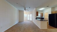 Located at 8108 Vinoy Blvd in Charlotte, NC, this single-floor residence offers a well-designed layout with a warm, neutral color palette throughout. The open-concept living area is finished with plush wall-to-wall carpeting and features crown molding, a ceiling fan, and elegant French doors that invite natural light and provide access to the outdoors. The living space flows seamlessly into the kitchen, which is separated by a peninsula counter with dark granite-style countertops. The kitchen is fully equipped with black appliances — including a range, microwave, refrigerator, and dishwasher — complemented by warm wood cabinetry and hardwood-style flooring. A dedicated laundry area with a washer is conveniently located just off the kitchen. The bedrooms are generously sized, each featuring ceiling fans, plush carpeting, and windows that allow for ample natural light. The bathroom is well-appointed with a tiled tub-and-shower combination, a white vanity with dark countertops, a large mirror, and hardwood-style flooring. Throughout the residence, clean white walls and consistent finishes create a cohesive and inviting atmosphere well suited for comfortable everyday living.