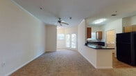 Located at 8108 Vinoy Blvd in Charlotte, NC, this single-floor residence offers a well-designed layout with a warm, neutral color palette throughout. The open-concept living area is finished with plush wall-to-wall carpeting and features crown molding, a ceiling fan, and elegant French doors that invite natural light and provide access to the outdoors. The living space flows seamlessly into the kitchen, which is separated by a peninsula counter with dark granite-style countertops. The kitchen is fully equipped with black appliances — including a range, microwave, refrigerator, and dishwasher — complemented by warm wood cabinetry and hardwood-style flooring. A dedicated laundry area with a washer is conveniently located just off the kitchen. The bedrooms are generously sized, each featuring ceiling fans, plush carpeting, and windows that allow for ample natural light. The bathroom is well-appointed with a tiled tub-and-shower combination, a white vanity with dark countertops, a large mirror, and hardwood-style flooring. Throughout the residence, clean white walls and consistent finishes create a cohesive and inviting atmosphere well suited for comfortable everyday living.