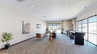 Located at 2109 E Anamosa St in Rapid City, South Dakota, this contemporary single-floor commercial space offers a well-organized and inviting layout designed for professional use. The entry reception area features warm wood-tone laminate flooring, a sleek front desk with wood accents, recessed lighting, and landscape artwork adorning the neutral-toned walls, setting a polished first impression for visitors.

Transitioning from the reception, the open lounge area is carpeted with a patterned, multi-tone floor covering that adds texture and warmth. Large windows along the exterior walls flood the space with natural light and provide views of the surrounding Rapid City landscape. The lounge is furnished with comfortable seating arrangements, including sofas, accent chairs, and round side tables, alongside a bar-height counter with stools — ideal for casual meetings or collaborative work.

Two connecting hallways facilitate smooth circulation throughout the space, guiding occupants between the public-facing areas and support rooms. Both bathrooms are ADA-compliant, each equipped with grab bars, wood-look flooring, wall-mounted paper towel dispensers, and vanity sinks, finished with neutral tones and charming decorative artwork. The overall design balances modern aesthetics with functional accessibility, creating a professional yet welcoming environment.