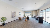 Located at 2109 E Anamosa St in Rapid City, South Dakota, this contemporary single-floor commercial space offers a well-organized and inviting layout designed for professional use. The entry reception area features warm wood-tone laminate flooring, a sleek front desk with wood accents, recessed lighting, and landscape artwork adorning the neutral-toned walls, setting a polished first impression for visitors.

Transitioning from the reception, the open lounge area is carpeted with a patterned, multi-tone floor covering that adds texture and warmth. Large windows along the exterior walls flood the space with natural light and provide views of the surrounding Rapid City landscape. The lounge is furnished with comfortable seating arrangements, including sofas, accent chairs, and round side tables, alongside a bar-height counter with stools — ideal for casual meetings or collaborative work.

Two connecting hallways facilitate smooth circulation throughout the space, guiding occupants between the public-facing areas and support rooms. Both bathrooms are ADA-compliant, each equipped with grab bars, wood-look flooring, wall-mounted paper towel dispensers, and vanity sinks, finished with neutral tones and charming decorative artwork. The overall design balances modern aesthetics with functional accessibility, creating a professional yet welcoming environment.