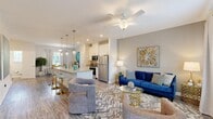 Located at 12001 Edenshire Rd in Chester, VA, this multi-level home offers a well-designed layout across three floors. The main living level serves as the heart of the home, combining the kitchen, dining room, and living room in an open-concept arrangement that promotes easy flow and natural light. The kitchen is outfitted with white shaker cabinetry, granite countertops, stainless steel appliances, and a large center island with bar seating and pendant lighting overhead — ideal for both everyday cooking and entertaining. The adjoining dining area features large windows with outdoor views, while the living room is spacious and bright, complete with a ceiling fan and a door providing direct outdoor access. Hardwood-style flooring runs throughout the main level, lending a clean, contemporary feel. The upper floors house two well-proportioned bedrooms, including a generously sized primary bedroom with plush carpeting, large windows overlooking greenery, and a dedicated closet. Two full bathrooms — each finished with granite vanity tops and white cabinetry — serve the household. The entry-level floor provides additional functional space, with hallways and staircases connecting all three levels cohesively. Neutral tones and modern finishes are carried throughout, creating a consistent and inviting aesthetic.