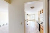 Located at 8266 Warbler Way in Liverpool, NY, this 2-bedroom, 1-bathroom residence offers a well-organized single-floor layout designed for comfortable everyday living. The galley-style kitchen is efficiently arranged with warm wood cabinetry, light countertops, tile flooring, and a full suite of appliances including an electric range, dishwasher, refrigerator, and built-in microwave. The kitchen flows toward the entry door, providing a practical and accessible layout. Adjacent to the kitchen, the combined dining and living area is bathed in natural light from a large window fitted with vertical blinds and a sliding glass door that opens to a private balcony overlooking the landscaped grounds and parking area. A pendant chandelier anchors the dining space, while a wall-mounted air conditioning unit and baseboard heating ensure year-round comfort. Both bedrooms feature soft carpeting, neutral walls, and baseboard heating, with the primary bedroom offering generous proportions and a closet with a wood-panel door. The full bathroom is finished with tile wainscoting, a tub-shower combination, a wood-tone vanity with ample storage, and a wide mirror with overhead lighting. The overall ambiance is clean, bright, and functional.