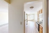 Located at 8266 Warbler Way in Liverpool, NY, this 2-bedroom, 1-bathroom residence offers a well-organized single-floor layout designed for comfortable everyday living. The galley-style kitchen is efficiently arranged with warm wood cabinetry, light countertops, tile flooring, and a full suite of appliances including an electric range, dishwasher, refrigerator, and built-in microwave. The kitchen flows toward the entry door, providing a practical and accessible layout. Adjacent to the kitchen, the combined dining and living area is bathed in natural light from a large window fitted with vertical blinds and a sliding glass door that opens to a private balcony overlooking the landscaped grounds and parking area. A pendant chandelier anchors the dining space, while a wall-mounted air conditioning unit and baseboard heating ensure year-round comfort. Both bedrooms feature soft carpeting, neutral walls, and baseboard heating, with the primary bedroom offering generous proportions and a closet with a wood-panel door. The full bathroom is finished with tile wainscoting, a tub-shower combination, a wood-tone vanity with ample storage, and a wide mirror with overhead lighting. The overall ambiance is clean, bright, and functional.