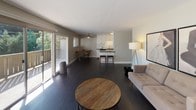 This single-floor residence offers a thoughtfully designed layout across two bedrooms and two bathrooms. The open-concept living and kitchen area serves as the heart of the home, featuring rich dark hardwood flooring that extends throughout the main living spaces. Sliding glass doors connect the living room to an outdoor deck, allowing natural light to pour in while providing easy access to the exterior.

The kitchen is well-equipped with white shaker cabinetry, dark countertops, stainless steel appliances including a refrigerator and dishwasher, and a central island with bar seating — ideal for casual dining or entertaining. A ceiling fan overhead adds both function and comfort to the open living area.

The primary bedroom is carpeted and features a mirrored sliding-door closet that amplifies the sense of space, along with a window offering natural views. The second bedroom is also carpeted and benefits from a garden-view window, providing a bright and comfortable retreat.

Both bathrooms are finished with dark countertops, undermount sinks, and large mirrors. One bathroom features a tub-shower combination, while the other offers a more compact, refined design. Clean, neutral tones throughout create a cohesive and modern ambiance across the entire space.