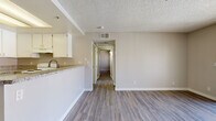 Located at 18215 Foothill Blvd in Fontana, CA, this 2-bedroom, 2-bathroom unit offers a practical and well-appointed single-floor layout. Wood-look laminate flooring runs throughout, providing a cohesive and easy-to-maintain surface across every room. The combined kitchen and living room serves as the heart of the unit, where white cabinetry, granite-style countertops, and a stainless steel sink give the kitchen a clean, functional feel. A white electric range and ample cabinet storage complete the cooking space. A breakfast bar-style counter opens the kitchen toward the living area, which is brightened by a ceiling fan and a sliding glass door that invites natural light and outdoor access. A central hallway connects the living spaces to the two bedrooms and bathrooms. Each bedroom features neutral-toned walls, wood-look flooring, textured ceilings, and windows fitted with vertical blinds for light control and privacy. The two bathrooms are finished with granite-top vanities, white cabinetry, and wood-look flooring — one featuring a shower-tub combination. Two closets provide additional storage. The overall palette of soft neutrals and white trim lends the space a clean, move-in-ready character.