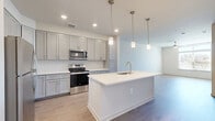 Located at 138 Rosewick Corner Pl in La Plata, MD, this well-designed one-bedroom, one-bathroom residence offers a thoughtfully organized single-floor layout with a clean, contemporary aesthetic throughout. Light-toned hardwood-style flooring flows seamlessly across the entire space, complementing the bright, neutral color palette on the walls and ceilings.

The open-concept kitchen, dining, and living area serves as the heart of the home. The kitchen is appointed with gray shaker-style cabinetry, a white subway tile backsplash, stainless steel appliances including a refrigerator, electric range, and over-the-range microwave, and a central island with a white countertop, undermount sink, and pendant lighting above. Recessed ceiling lights provide additional illumination throughout the shared living space.

The bedroom is a well-proportioned, quiet retreat featuring a ceiling fan, a large window that brings in abundant natural light and outdoor views, and access to two closets for ample storage.

The full bathroom is finished with a wide dual-sink vanity featuring gray shaker cabinetry, a white countertop, a large mirror, and subway tile detailing in the shower area. A dedicated in-unit laundry room with wire shelving and washer/dryer hookups adds everyday convenience to this move-in-ready residence.