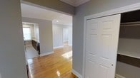 This single-floor space offers a thoughtfully designed layout with a seamless flow between rooms. The interior is finished with warm, polished hardwood floors that run throughout, reflecting natural light and adding a sense of warmth and continuity to the space. Walls are painted in a soft, neutral gray tone, creating a calm and versatile backdrop that complements a variety of furnishing styles.

Crown molding and crisp white baseboards add a classic architectural detail, lending an air of refinement to the overall design. Recessed lighting is integrated into the ceilings, providing clean, even illumination across the open areas. Wide doorways and open archways connect the living areas, promoting a spacious and airy feel as you move through the home.

A utility area with laundry appliances is visible from the main corridor, offering practical convenience. Interior doors feature a paneled design with bright white finishes, consistent with the home's clean aesthetic. The overall ambiance is bright, neutral, and move-in ready, with a layout that lends itself well to comfortable everyday living. The combination of classic trim work, polished floors, and soft wall tones creates a welcoming and functional environment throughout.