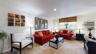 This single-floor residence offers a thoughtfully arranged layout that balances comfort and functionality across its main living areas. The living room serves as the centerpiece of the home, featuring neutral carpeted flooring, recessed lighting, and clean white walls that create a bright, welcoming atmosphere. A window dressed with a patterned roman shade allows natural light to filter in while providing outdoor views, complementing the room's warm, inviting character. Framed wall art and coordinated furnishings complete the polished aesthetic.

The kitchen is efficiently designed with white cabinetry providing ample storage, dark granite-style countertops, a gas range, and a stainless steel sink. The clean, functional layout makes excellent use of the available space.

The bedroom is generously sized, featuring soft carpeting, multiple closets offering considerable storage, and windows that bring in natural light. The room comfortably accommodates a large bed and additional furniture.

The bathroom is finished with classic tile wainscoting, tile flooring, a wood-toned vanity with a light countertop, and framed mirrors, giving it a clean and timeless appearance. Overall, this residence presents a cohesive design with practical features throughout every room.