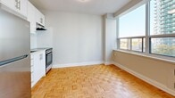 Located at 100 Roehampton Ave in the vibrant Midtown Toronto neighbourhood, this efficient studio unit offers a well-organized layout across a single floor. The living area is bright and airy, benefiting from a wide bank of floor-to-ceiling windows that frame sweeping views of the surrounding Toronto cityscape, flooding the space with natural light. Classic parquet hardwood flooring runs throughout the main living and kitchen areas, adding warmth and a timeless character to the unit.

The kitchen is positioned compactly along one wall and features white cabinetry and a stainless steel range, making efficient use of the available space. A dedicated entrance leads into the unit, with two closets providing practical storage solutions.

The bathroom is finished with white subway tile walls and includes a glass-enclosed shower-tub combination and a toilet, maintaining a clean and functional aesthetic. A baseboard heating unit runs beneath the living room windows, ensuring comfortable warmth during Toronto's colder months.

The overall ambiance of the unit is light, neutral, and functional, with white walls throughout that complement the natural tones of the parquet floors. Its Midtown Toronto location places residents close to transit, dining, and the amenities of Yonge and Eglinton.