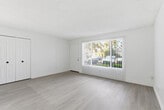Located at 5200 Canyon Crest Dr in Riverside, CA, this single-floor, 3-bedroom, 1-bathroom unit offers a clean, updated interior with a bright and neutral color palette throughout. The open living and dining area is filled with natural light from a large front-facing window fitted with vertical blinds, and features light wood-look flooring and a ceiling fan, creating a comfortable and airy atmosphere. A pass-through opening connects this space to the galley-style kitchen, which is outfitted with white shaker cabinetry, black hardware, light countertops, a stainless steel sink, recessed lighting, and matching appliances including an electric range and over-the-range microwave. The three bedrooms are carpeted for comfort and each include windows with vertical blinds that bring in natural light and views of surrounding greenery. Two closets provide ample storage across the unit. The full bathroom is thoughtfully appointed with a white vanity, medicine cabinet mirror, modern light fixture, matte black hardware accents, and a tub-shower combination with sliding glass doors and marble-style tile surround. Light wood-look flooring continues through the bathroom, tying the space together with a cohesive, contemporary aesthetic.